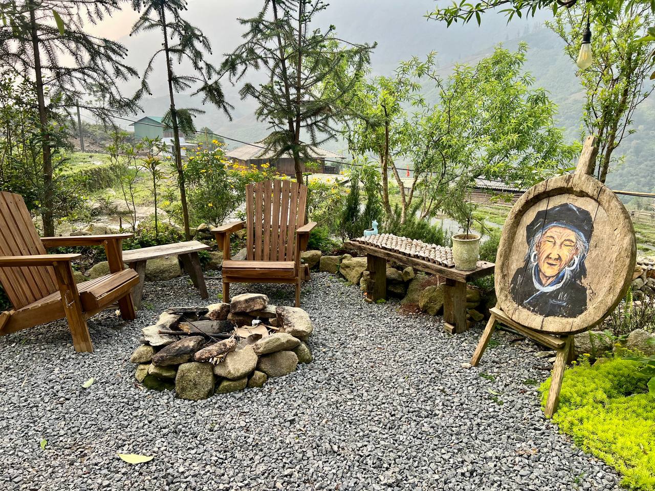 The garden at Pavi Cafe — fire pit, Adirondack chairs, carved art